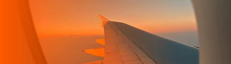 Airplane Wing View at Sunset Through Window