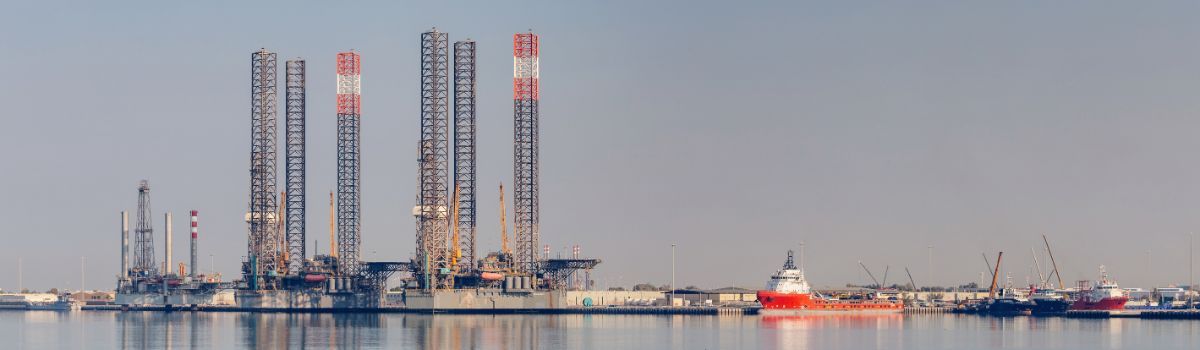 Abu Dhabi, UAE_ Jackup oil rig and platform supply vessel staying in harbor in calm water with cloudy sky