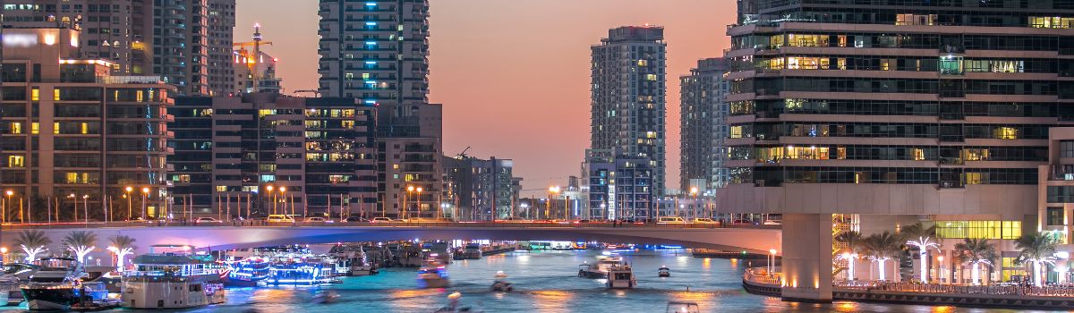 Dubai Marina waterfront with towers and yachts from bridge in Dubai day to night transition timelapse, United Arab Emirates. District with artificial canal after sunset
